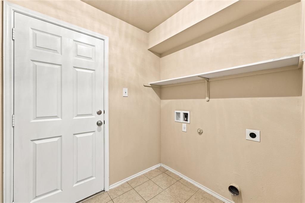 Dedicated laundry area featuring tile flooring, a white paneled door, and integrated shelving