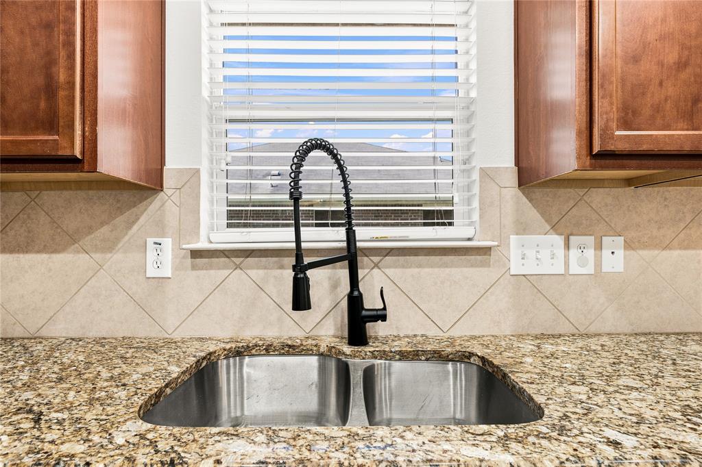 Double basin stainless steel sink with a matte black pull-down faucet, set into a granite countertop