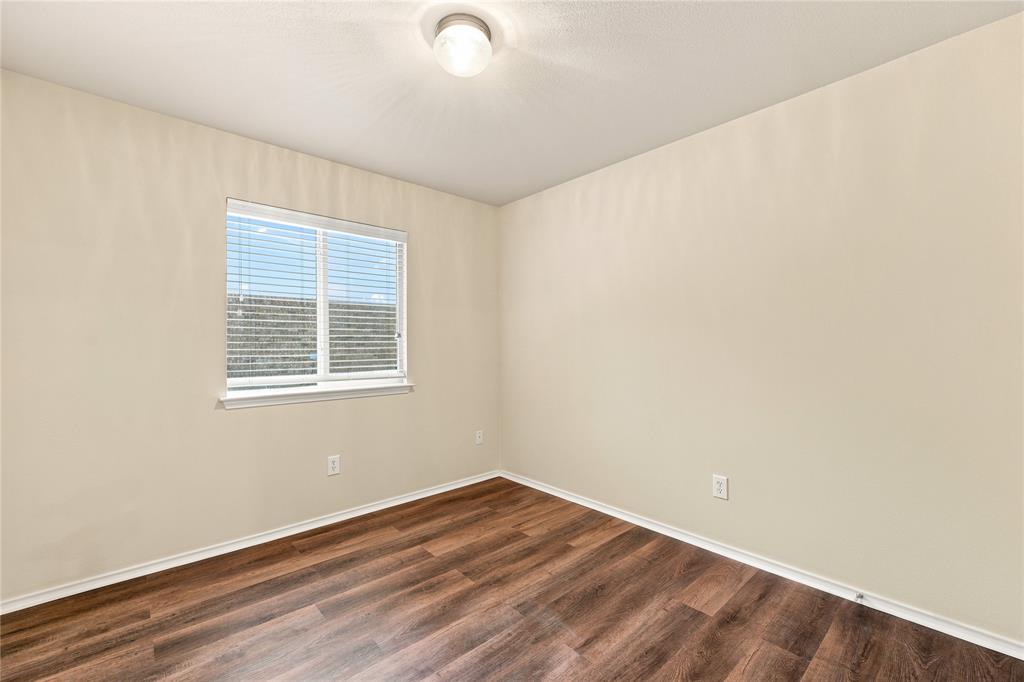 Room with wood-finish flooring, a double-hung window with blinds, and a flush mount ceiling light fixture