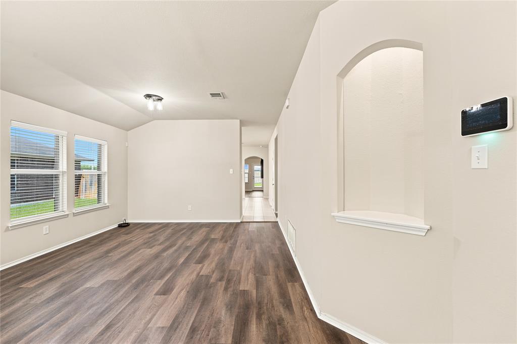 Spacious room featuring wood-finish flooring, light-colored walls, and multiple windows with blinds