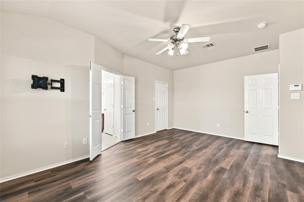 Spacious room featuring wood-finish flooring, light-toned walls, and a ceiling fan with integrated lighting