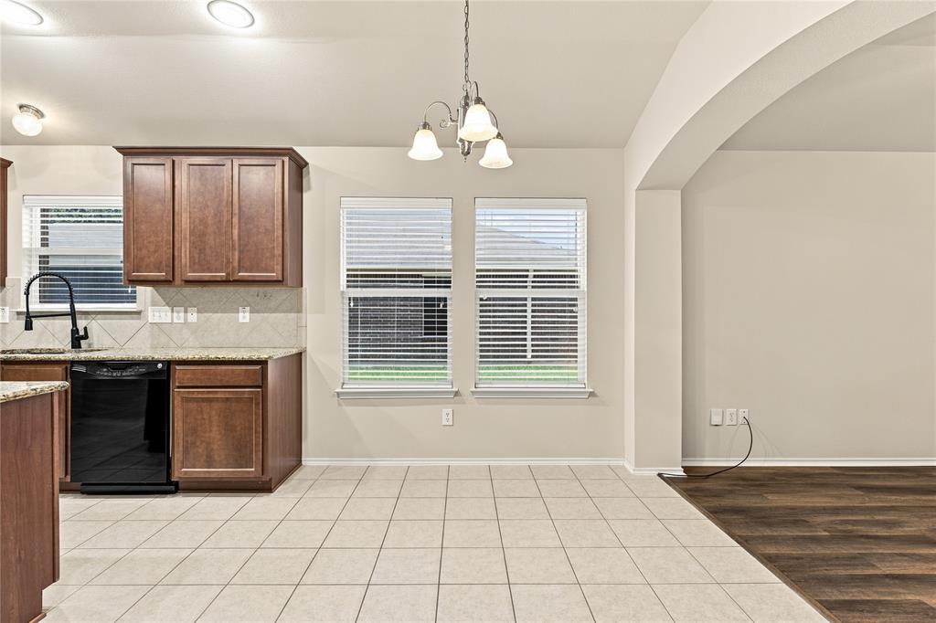 Kitchen and dining area featuring wood cabinetry, black appliances, tile flooring, and an arched entryway
