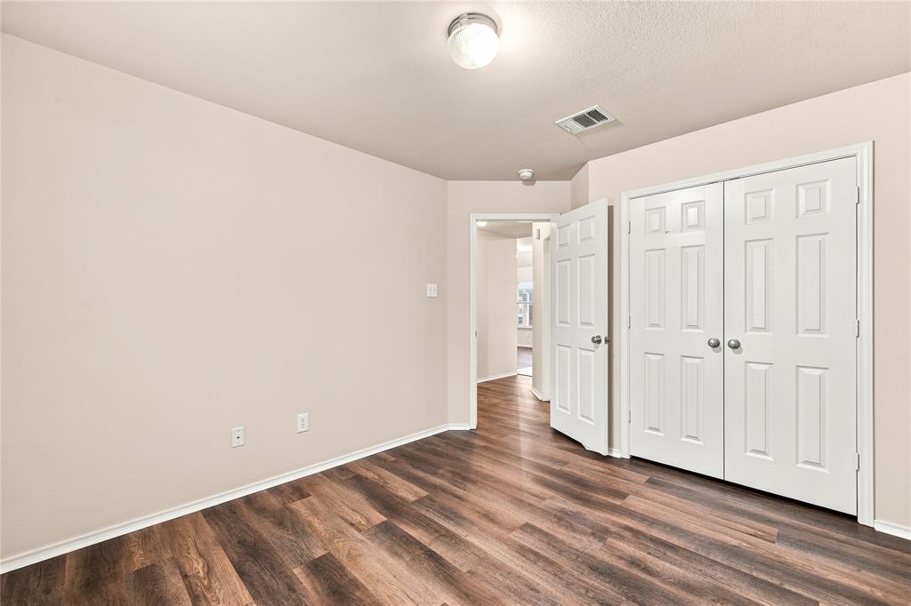 Room featuring wood-finish flooring, light-toned walls, white baseboards, and a ceiling-mounted light fixture