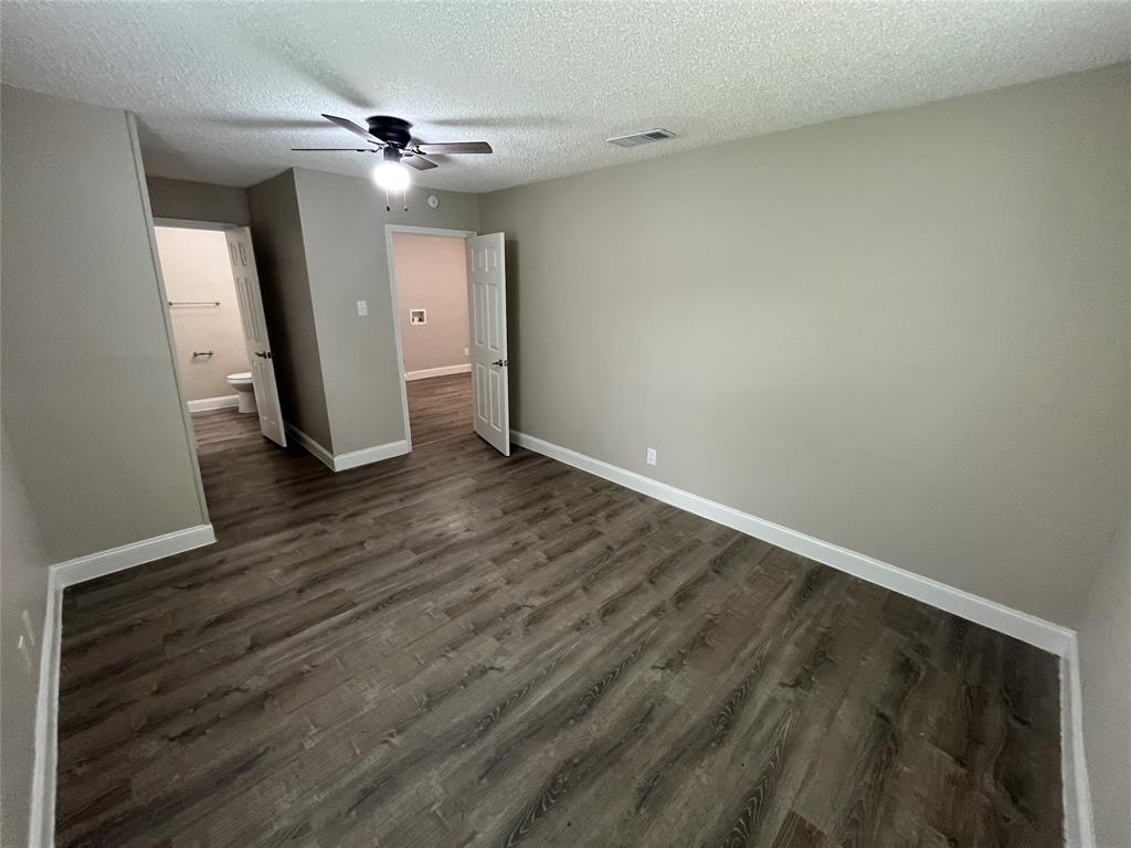 Spacious room featuring wood-finish flooring, light neutral wall paint, and white baseboards