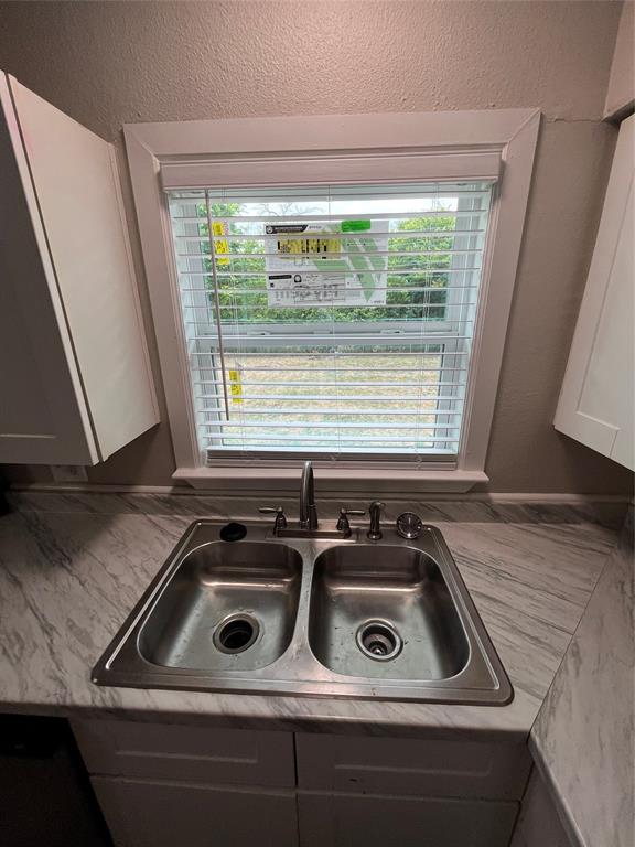 Stainless steel double basin sink with an arched faucet set into a marble-look laminate countertop