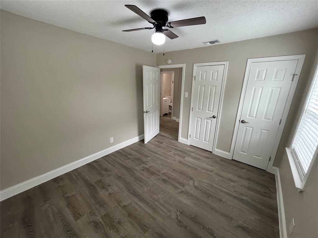 Room featuring wood-finish flooring, neutral wall tones, and a ceiling fan with light fixture