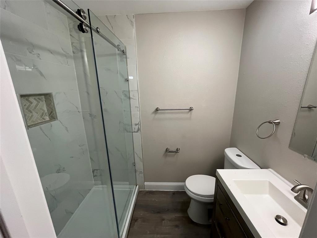 Contemporary bathroom featuring a spacious shower with sliding glass doors, white marble-look tile, and a recessed niche with herringbone pattern accent tile