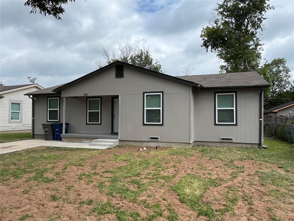 Single-story residence featuring light gray siding with dark trim, a covered front porch, and a concrete driveway