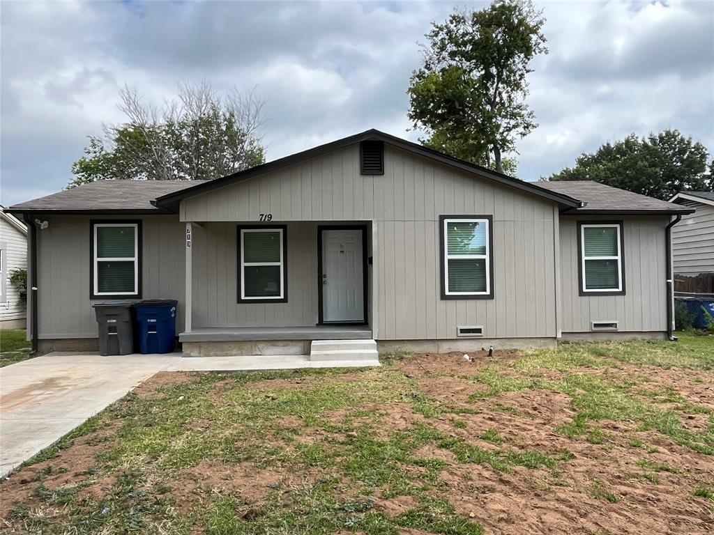Single-story residence featuring light gray vertical panel siding with dark trim, a dark asphalt shingle roof, and a front concrete porch