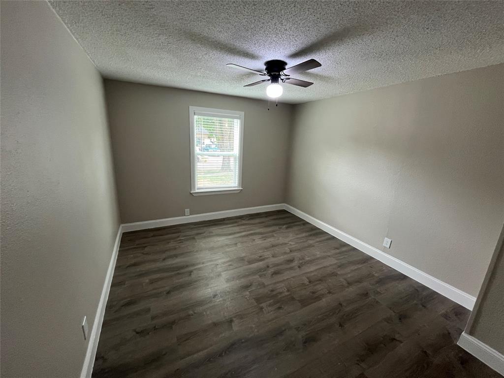 Bedroom featuring wood-finish flooring, neutral wall tones, a window with blinds, white baseboards, and a ceiling fan with integrated lighting