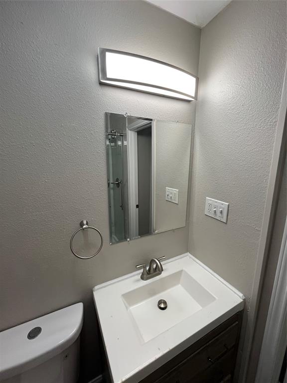 Bathroom vanity featuring an integrated sink, brushed nickel faucet, and a wood-finish cabinet with dark hardware