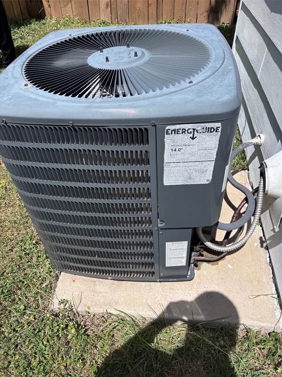 Outdoor HVAC unit with visible fan and EnergyGuide label, mounted on a concrete pad