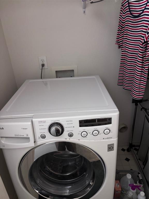 Dedicated laundry area featuring a front-loading appliance and wall-mounted electrical outlet