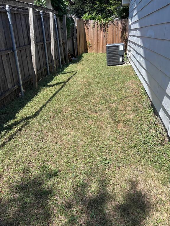 Side yard space featuring a wood fence, a second wood-paneled fence, and a central air conditioning unit