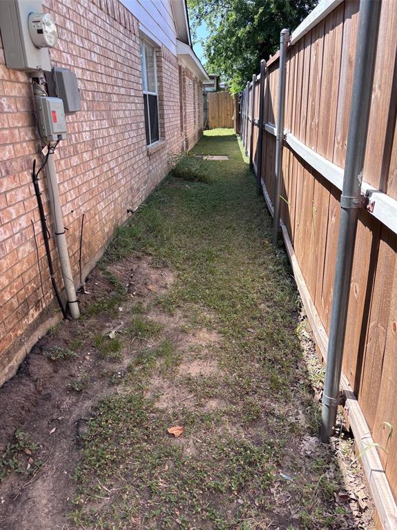 Side yard featuring a red brick exterior, white trim, and a wood privacy fence