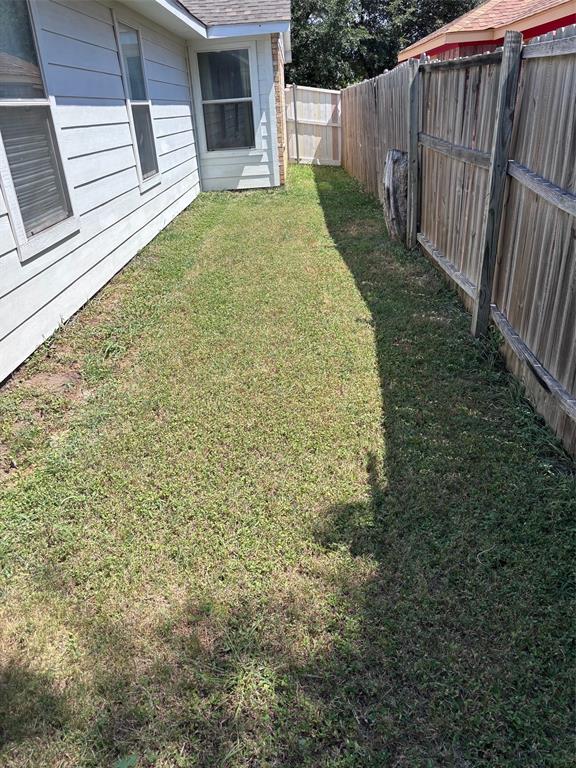 Side yard featuring a wooden privacy fence, horizontal siding, and multiple windows