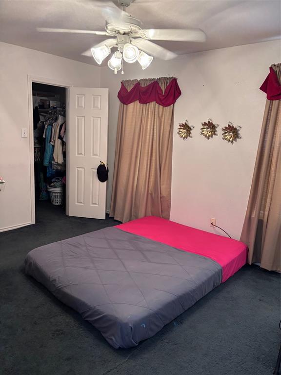 Carpeted room featuring a ceiling fan with integrated lighting, a white panel door, and an open closet