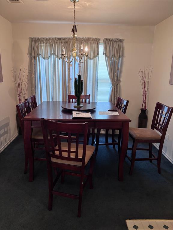 Dining space featuring dark wood-finish flooring, a brass-tone chandelier, and light-toned walls