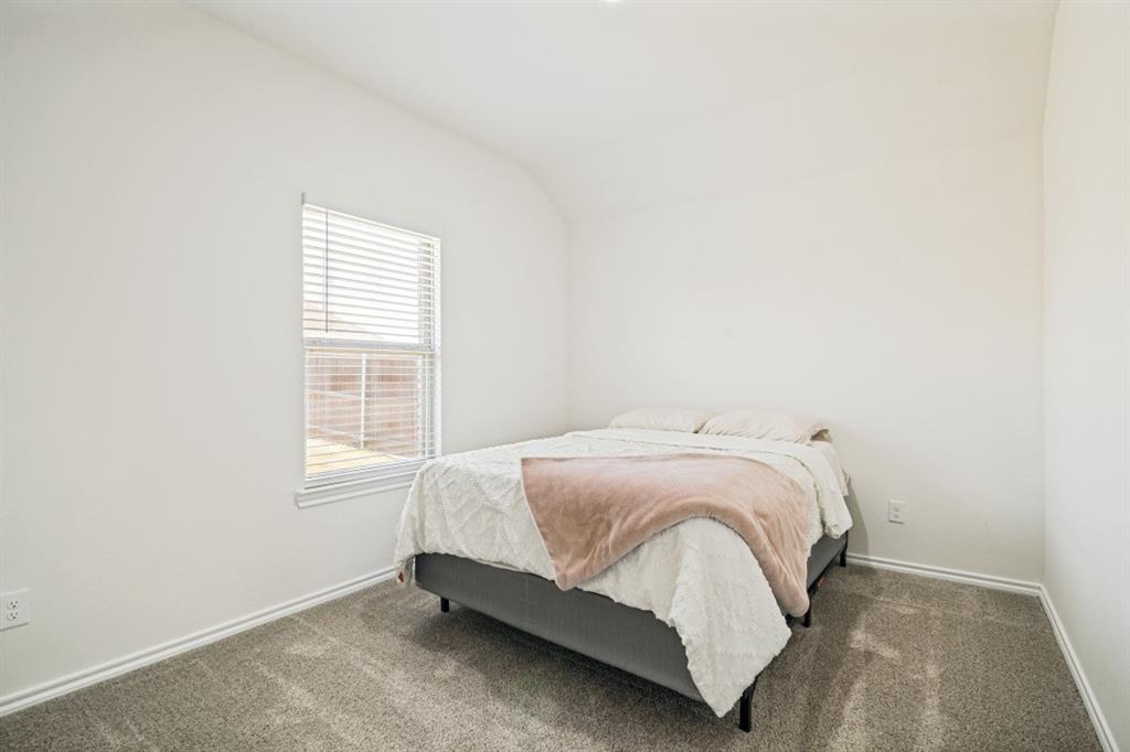 Bright room featuring neutral-toned carpeting, white walls, and a single window with horizontal blinds