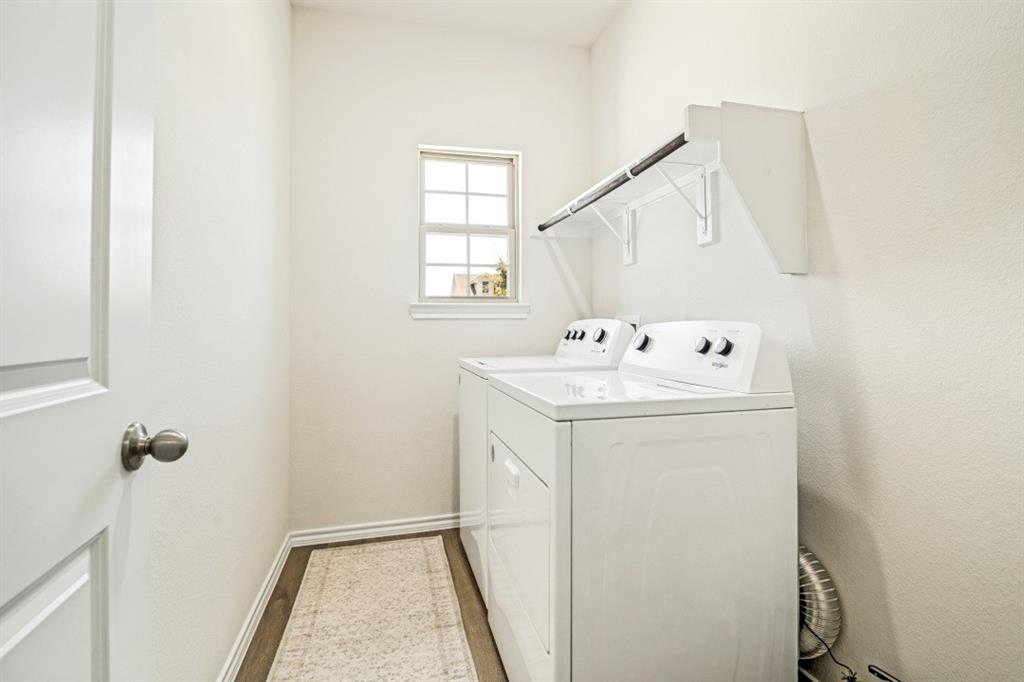 Dedicated utility room featuring wood-finish flooring, a window with natural light, and a functional hanging rod with shelving