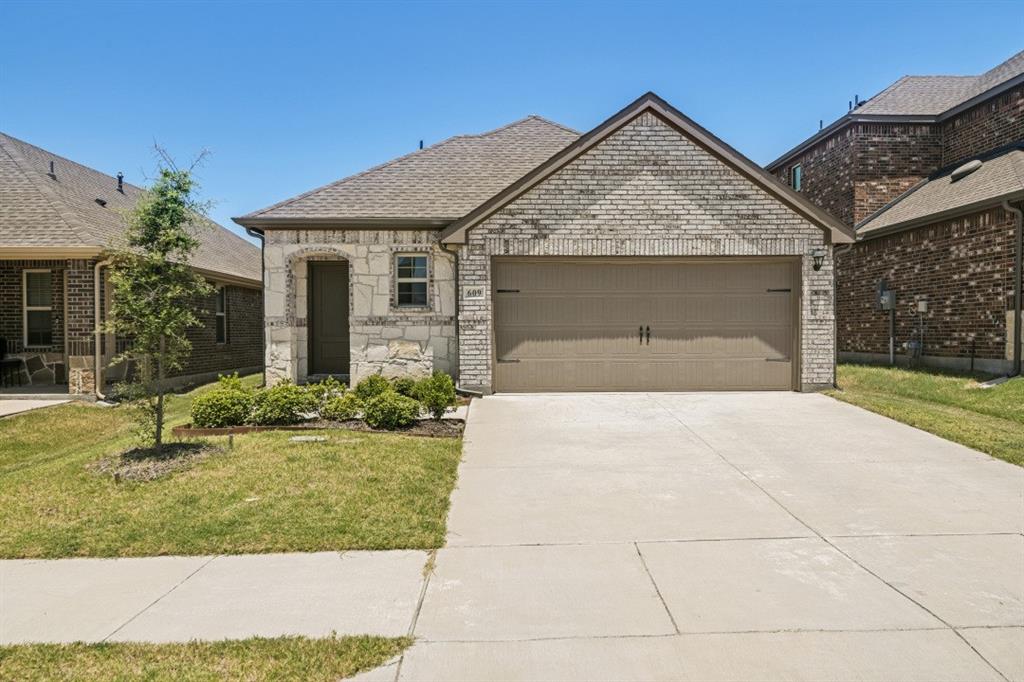 Two-car garage with a concrete driveway, complemented by a stone and brick facade