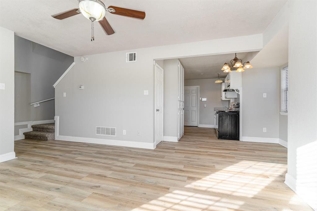 Spacious living area featuring wood-finish flooring, a ceiling fan, and light gray wall paint