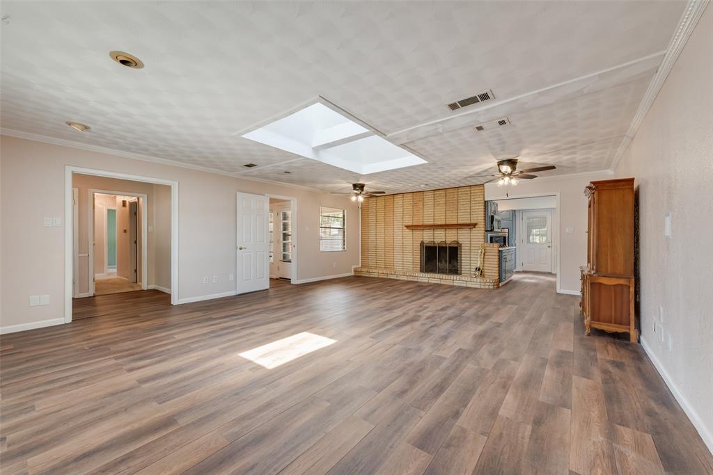 Spacious living area featuring a brick fireplace with a hearth and large skylight