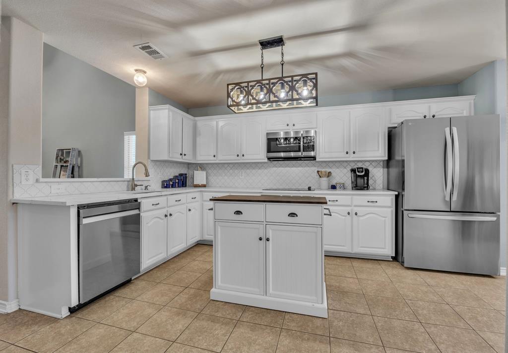 Renovated kitchen with quartz countertops, stainless steel appliances, backsplash, and new lighting.