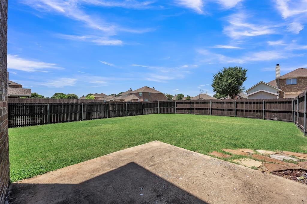 Expansive backyard featuring a manicured lawn, full perimeter fencing, and a concrete patio