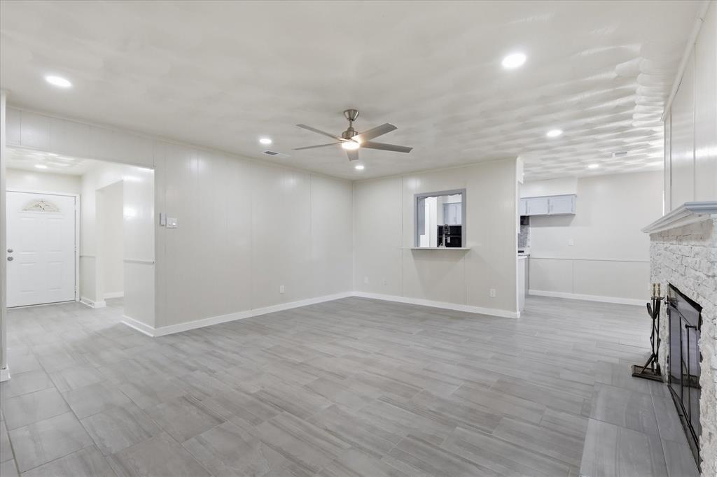 Spacious living area featuring light gray wood-finish flooring, recessed lighting, and a contemporary ceiling fan