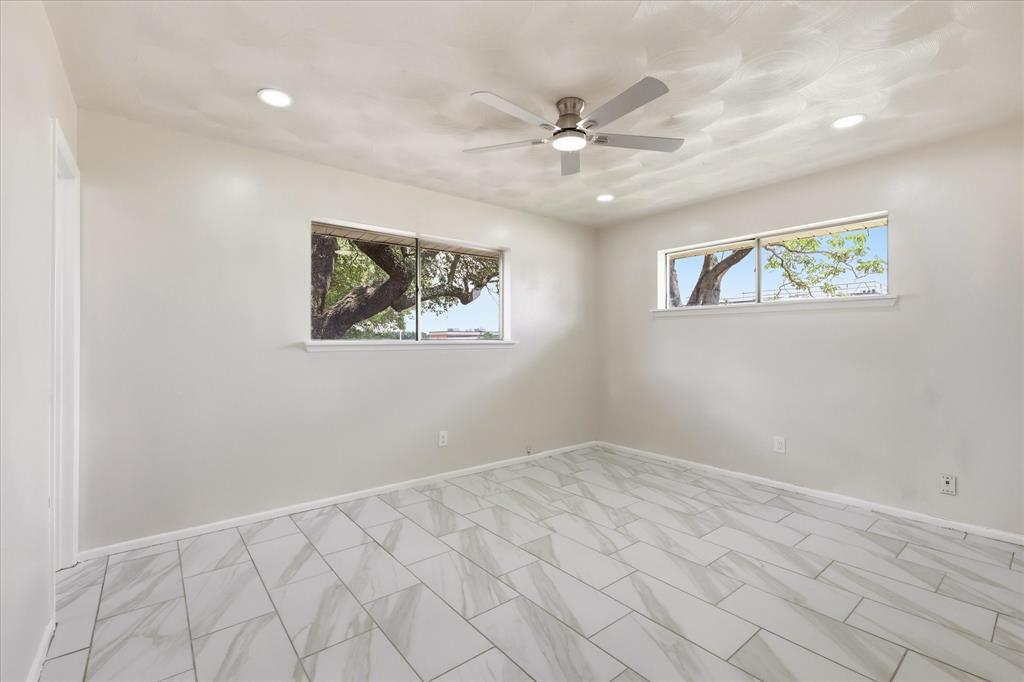 Recessed lighting illuminates this room featuring light-colored walls and large format tile flooring