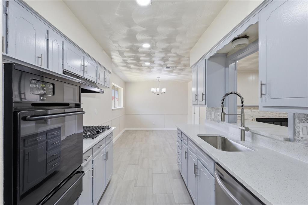 Galley kitchen featuring light-toned cabinetry, light-toned countertops, tile flooring, a built-in oven, and a gas cooktop
