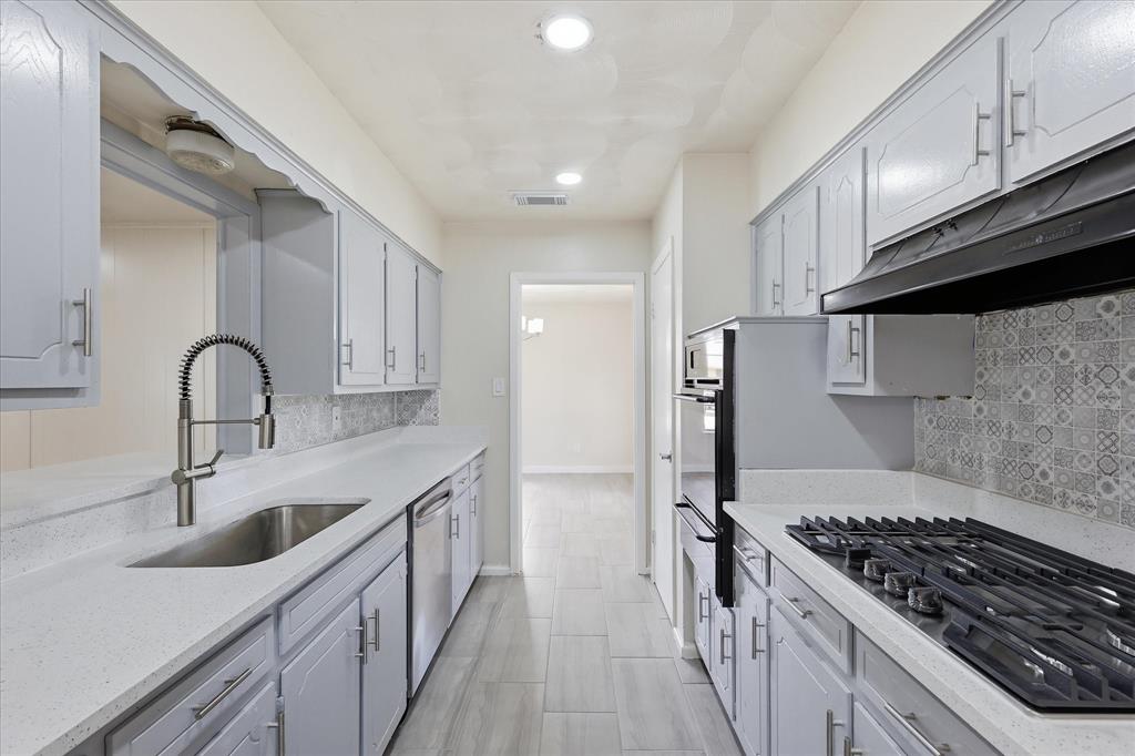 Galley kitchen featuring light gray cabinetry, light-toned countertops, and a decorative tile backsplash