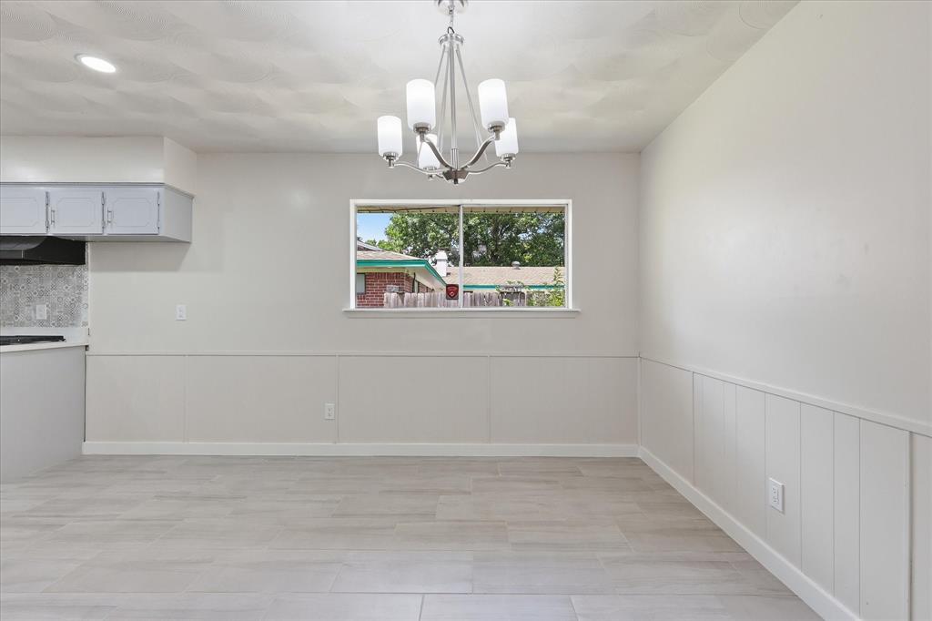 Dining area featuring a contemporary chandelier, light-toned wood-look tile flooring, and a window providing natural light