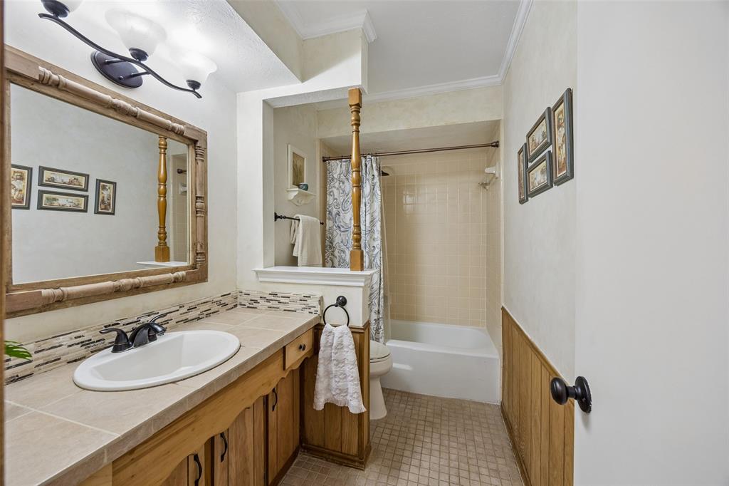 Bathroom featuring a single vanity with wood cabinetry, a light-toned countertop, and a tiled backsplash