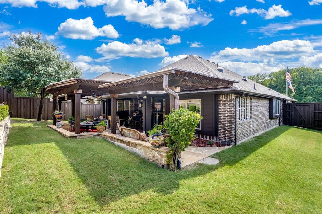 Expansive backyard featuring a stone patio, twin pergolas, and a manicured lawn