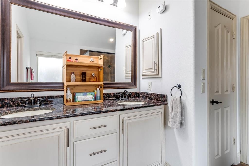 Double vanity with under-mount sinks, dark stone countertop, and custom white cabinetry