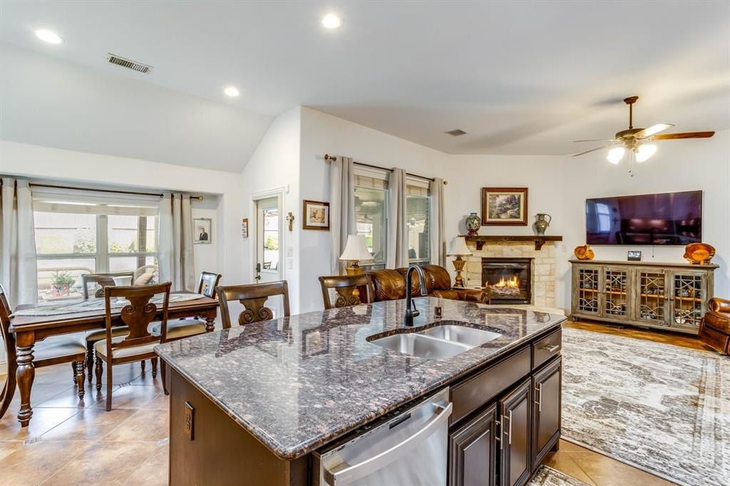 Kitchen island with dark cabinetry and a speckled countertop, featuring an undermount double-basin stainless steel sink