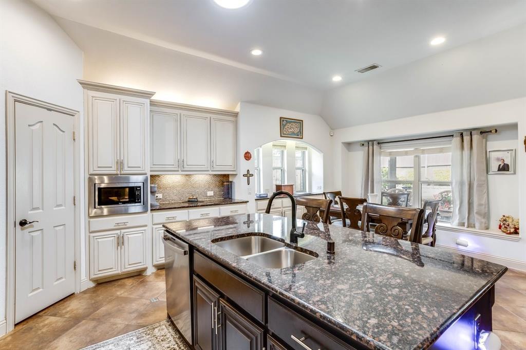 Kitchen featuring a large island with a double basin sink, granite countertops, light wood-finish cabinetry, and stainless steel appliances