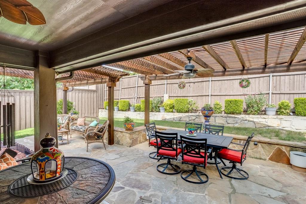 Expansive outdoor patio featuring flagstone paving, a wood ceiling with a ceiling fan, and a wood pergola extension