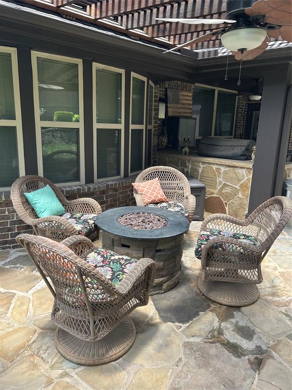 Flagstone patio with a built-in fire pit, covered by a wooden pergola, and equipped with a ceiling fan