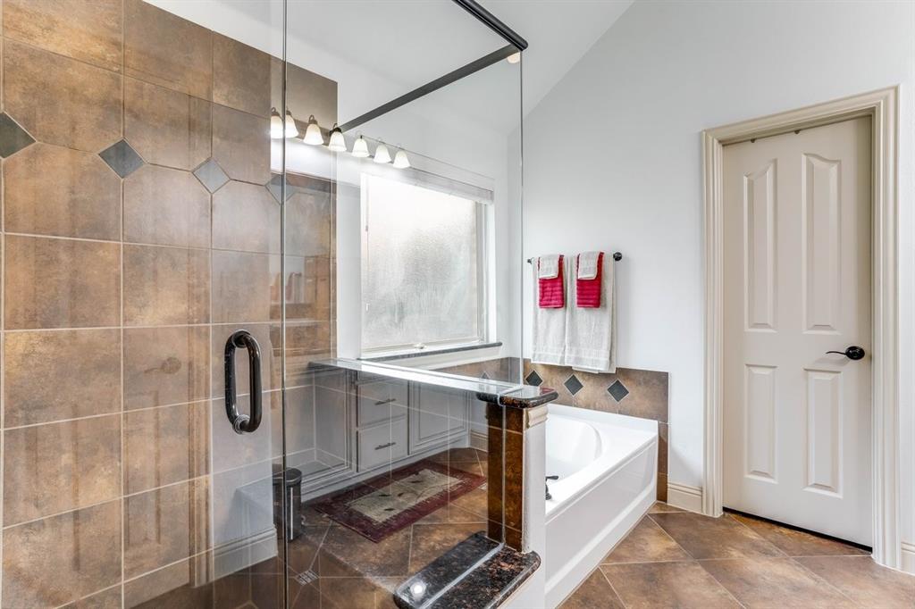 Glass-enclosed shower with brown and dark accent tiling