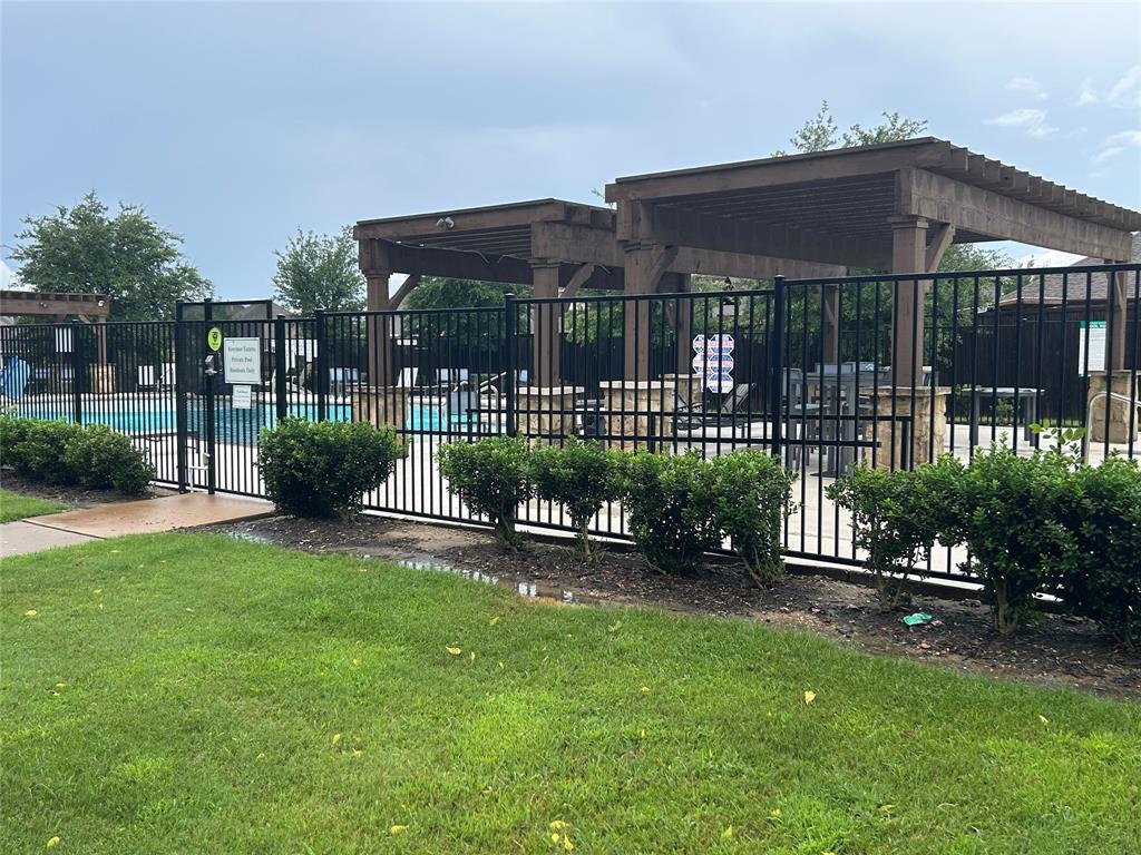 Outdoor pool area featuring black wrought iron fencing, multiple pergolas, and stone pillar accents