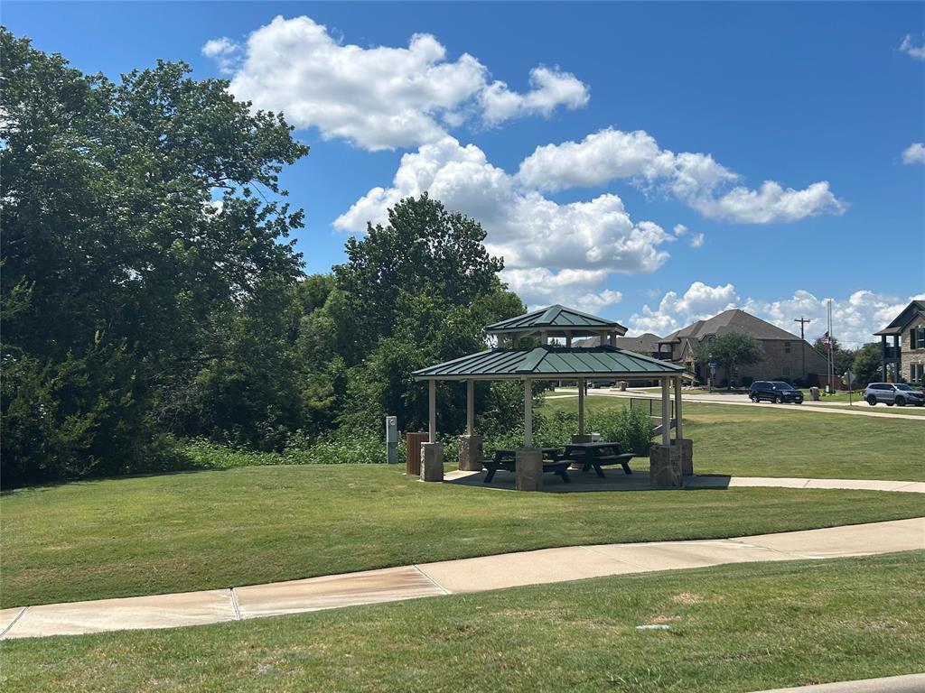 Community gazebo with a tiered green roof, stone-clad pillars, and a picnic table