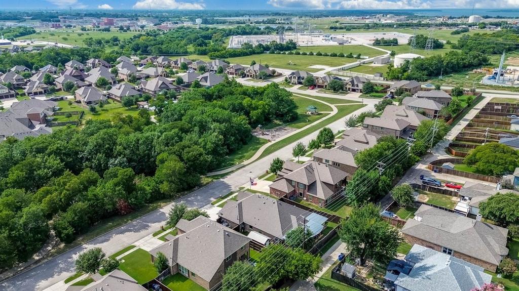 Aerial perspective of a residential neighborhood featuring established homes with gabled roofs, mature trees, and paved streets