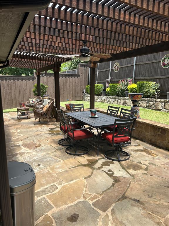 Expansive flagstone patio featuring a large wooden pergola with an integrated ceiling fan