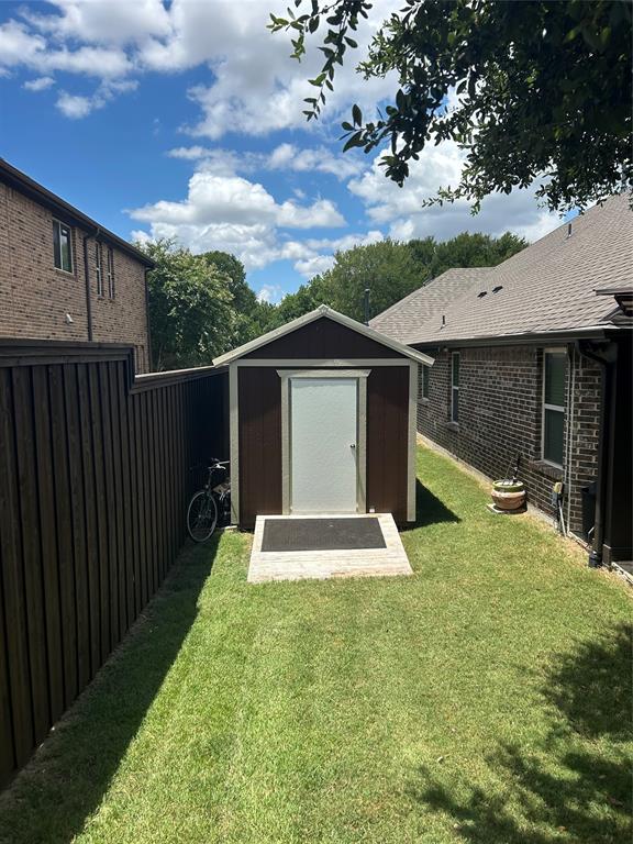 Backyard storage shed with a light-colored door, dark siding, and a gabled roof