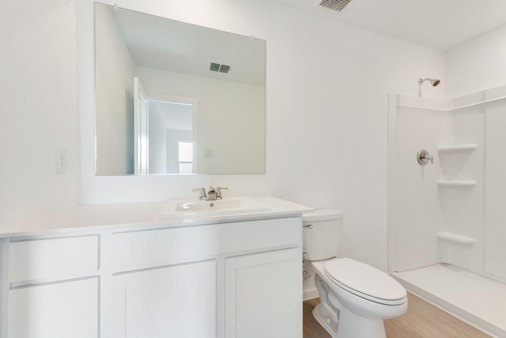 Bathroom featuring vanity, a shower, and wood finished floors