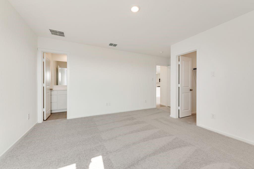 Unfurnished bedroom featuring light carpet and connected bathroom