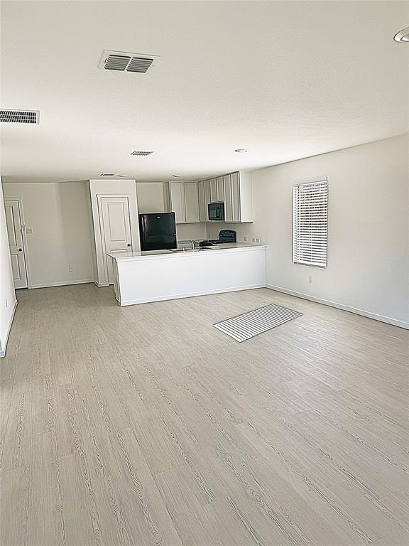 Unfurnished living room with light wood-style flooring and baseboards Unfurnished living room with light wood-style flooring and baseboards